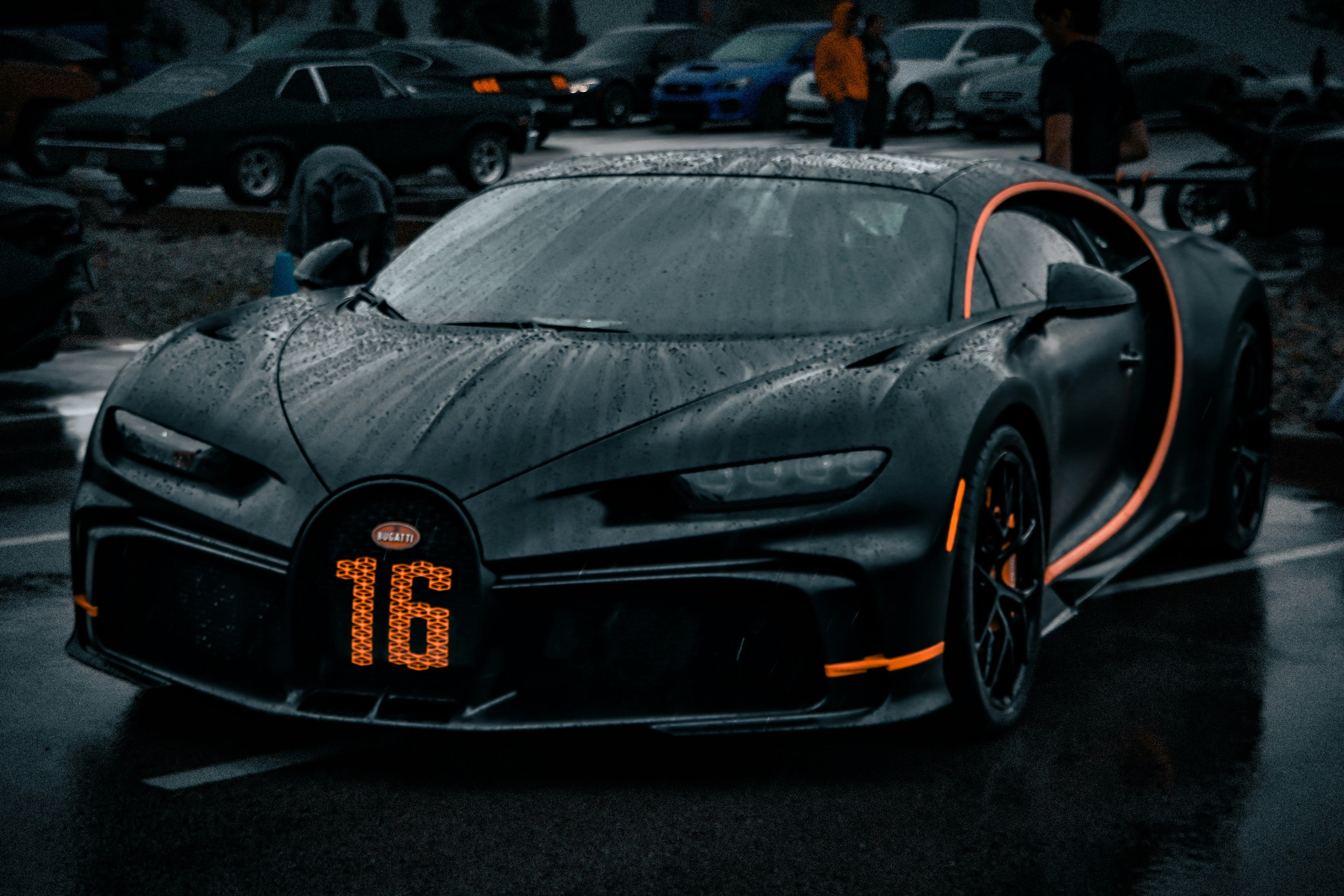 Black Bugatti car with orange accents on a dark street